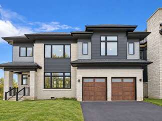 This stunning modern home boasts a striking facade with a combination of dark gray siding and light stone accents.
