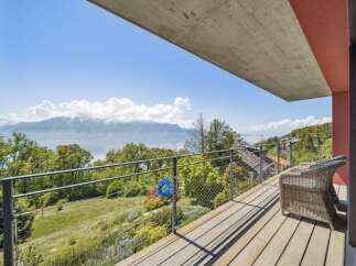Enjoy breathtaking panoramic views of snow-capped mountains and a serene lake from this modern balcony.