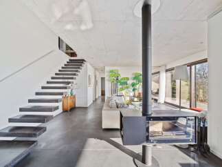 Experience modern living in this stunning open-concept home featuring a floating staircase and a sleek, central fireplace.