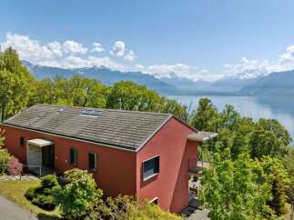 Experience breathtaking panoramic views of snow-capped mountains and a serene lake from this modern red villa.