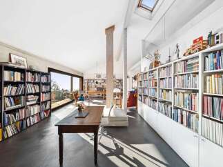This spacious home office boasts an abundance of natural light streaming through large windows and a skylight, creating an inviting atmosphere for work and study.