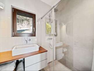 Experience modern comfort in this beautifully appointed bathroom, featuring a sleek vessel sink atop a warm wooden vanity.