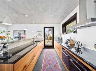 Experience modern living in this sleek kitchen featuring a concrete ceiling and minimalist pendant lights.