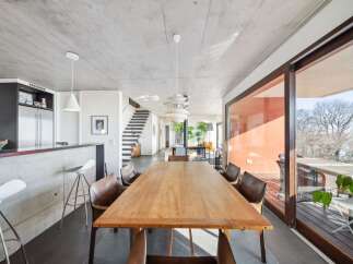 Experience modern living in this spacious open-plan home featuring a sleek concrete kitchen island with bar seating and a large wooden dining table perfect for gatherings.