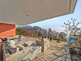 Experience luxurious outdoor living on this expansive wooden deck, featuring comfortable wicker seating and a dining area perfect for al fresco meals.