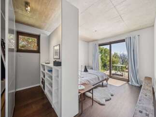 This modern bedroom features a minimalist design with a concrete ceiling and dark wood floors.
