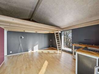Discover this unique loft-style living space featuring exposed wooden beams and a modern, minimalist aesthetic.