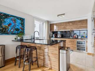 This modern kitchen boasts a sleek design with rich wood cabinetry and a stunning black granite countertop island.
