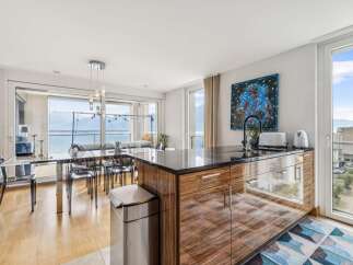 Experience modern living in this stunning open-concept kitchen and dining area, boasting breathtaking lake and mountain views through expansive floor-to-ceiling windows.