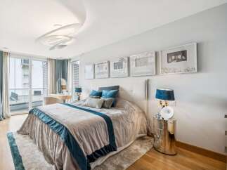 Experience luxury and comfort in this elegantly appointed bedroom, featuring a plush king-size bed adorned with sophisticated blue and grey linens.