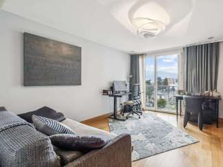 This modern living space offers a comfortable sofa and a dedicated workspace with a computer and ergonomic chair.