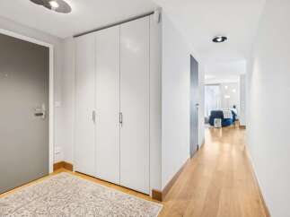 Step into this inviting hallway featuring a sleek grey door and a wall of white built-in cabinets, perfect for ample storage.