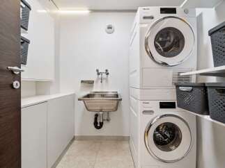 Discover this modern laundry room featuring a stacked Miele washer and dryer for efficient space utilization.