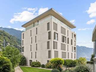 Experience modern luxury in this stunning multi-story building, featuring a sleek facade and expansive glass balconies offering breathtaking mountain and lake views.
