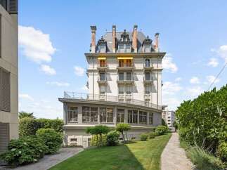 Discover this stunning property featuring a grand, multi-story building with classic architectural details, including ornate balconies and a mansard roof.