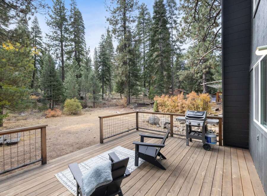 Enjoy outdoor living on this spacious wooden deck, perfect for entertaining or relaxing amidst a serene forest setting.
