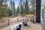 Enjoy outdoor living on this spacious wooden deck, perfect for entertaining or relaxing amidst a serene forest setting.