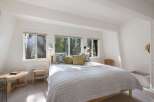 Experience serene living in this charming bedroom, bathed in natural light from large windows overlooking a lush forest.