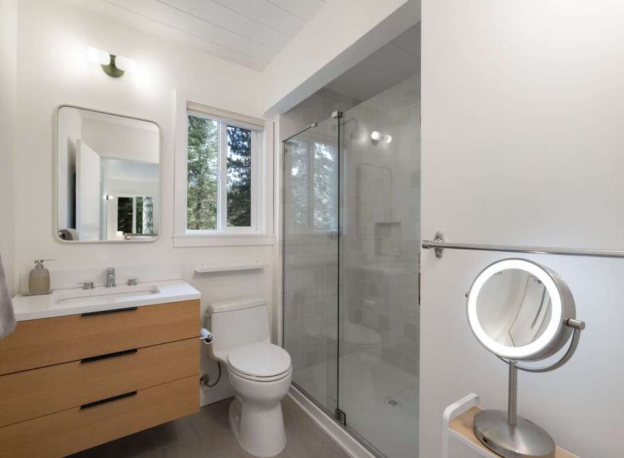 This modern bathroom features a sleek floating vanity with ample drawer storage, complemented by a minimalist white countertop and sink.