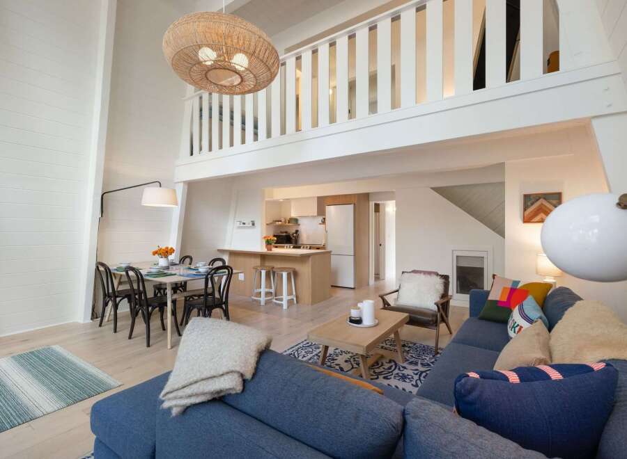 This open-concept living space boasts a stunning vaulted ceiling with a large woven pendant light, creating an airy and spacious feel.