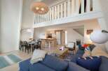 This open-concept living space boasts a stunning vaulted ceiling with a large woven pendant light, creating an airy and spacious feel.