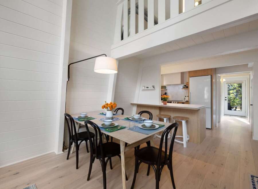 Experience bright and airy living in this charming dining area, featuring a light wood table set for four and elegant black chairs.
