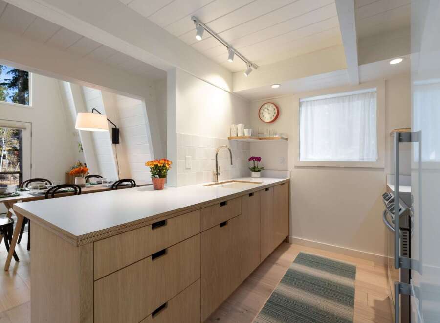 This modern kitchen features light wood cabinetry and a sleek white countertop, perfect for meal preparation.