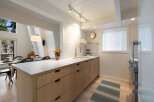 This modern kitchen features light wood cabinetry and a sleek white countertop, perfect for meal preparation.