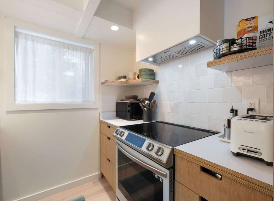 This modern kitchen features sleek, light wood cabinetry and a white subway tile backsplash, creating a bright and airy atmosphere.