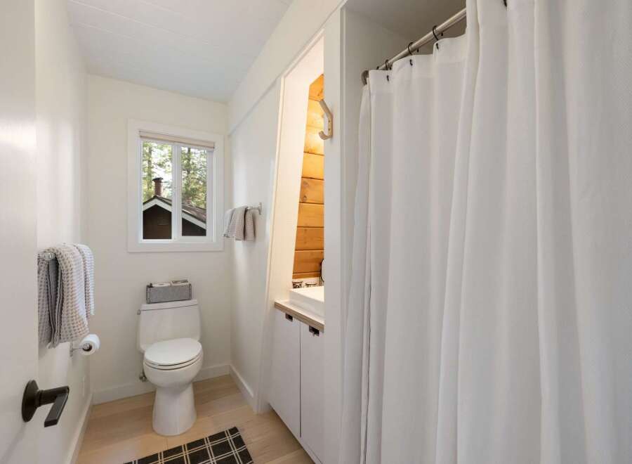 This bright and airy bathroom features a clean white toilet and a vanity with ample storage.