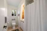 This bright and airy bathroom features a clean white toilet and a vanity with ample storage.