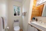This bright and airy bathroom features a modern white vanity with a sleek faucet, complemented by warm wooden accents on the wall.