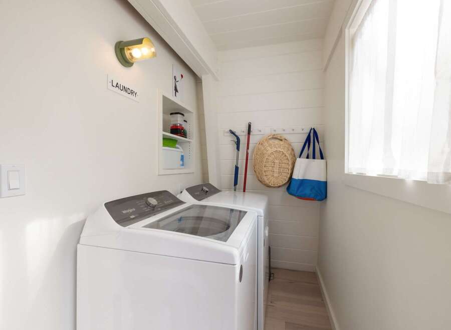 This laundry room boasts a modern Whirlpool top-load washer and dryer, perfect for handling family-sized loads.