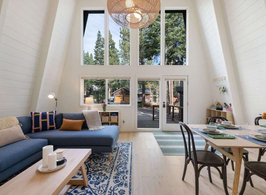 Experience the charm of this A-frame cabin, boasting a stunning vaulted ceiling with expansive windows that flood the living space with natural light.