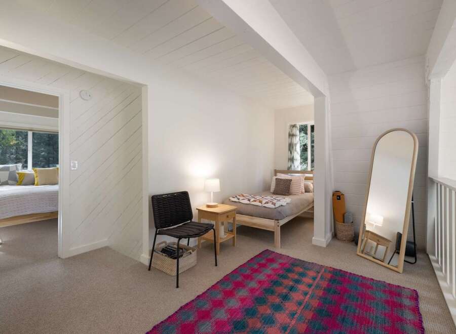 Discover this charming bedroom featuring a cozy bed with decorative pillows and a vibrant geometric rug.