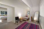Discover this charming bedroom featuring a cozy bed with decorative pillows and a vibrant geometric rug.