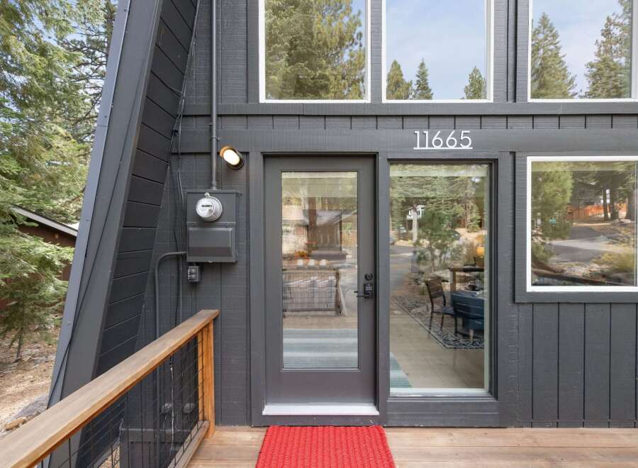 Discover this charming A-frame home featuring a modern dark gray exterior and a welcoming wooden deck.