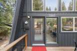 Discover this charming A-frame home featuring a modern dark gray exterior and a welcoming wooden deck.