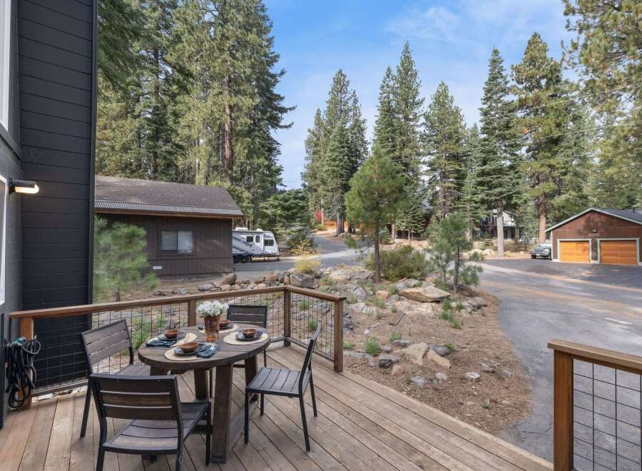 Enjoy outdoor dining on the spacious wooden deck, complete with a table set for four and a scenic view of the surrounding pine forest.