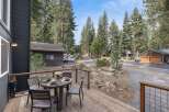 Enjoy outdoor dining on the spacious wooden deck, complete with a table set for four and a scenic view of the surrounding pine forest.