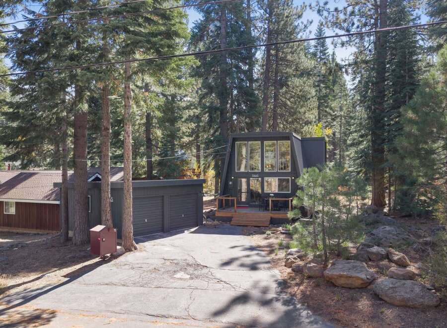 Discover this modern A-frame home nestled amongst tall pine trees, offering a unique architectural style and a serene natural setting.