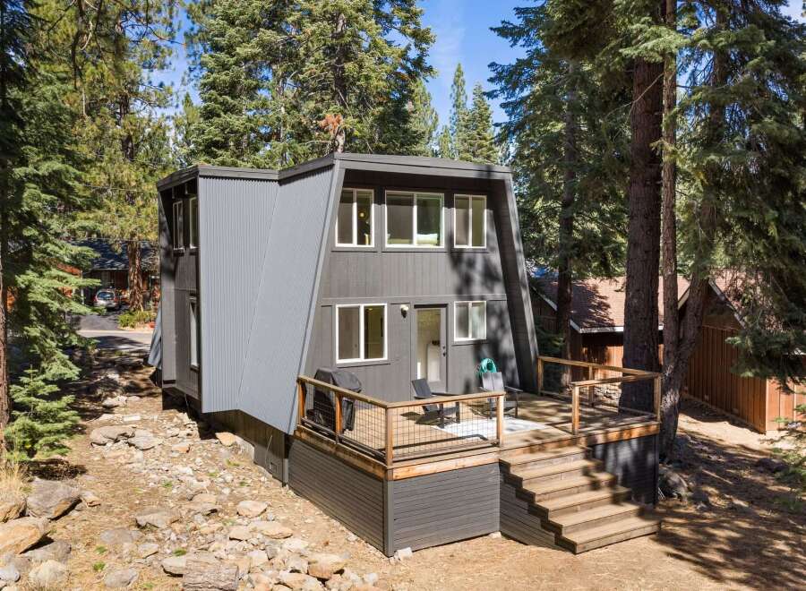 Discover this modern A-frame home nestled among tall pine trees, offering a unique architectural design and a serene natural setting.