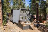 Discover this modern A-frame home nestled among tall pine trees, offering a unique architectural design and a serene natural setting.
