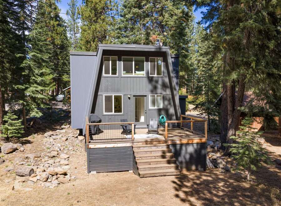 Discover this modern A-frame home nestled among tall pine trees, offering a unique architectural design and a serene natural setting.
