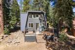Discover this modern A-frame home nestled among tall pine trees, offering a unique architectural design and a serene natural setting.