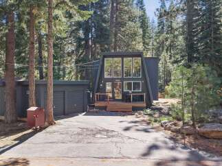 Discover this charming A-frame home nestled among tall pine trees, offering a unique architectural style and a serene forest setting.