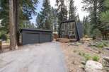Discover this modern A-frame home nestled among tall pine trees, featuring a striking dark exterior and expansive windows.