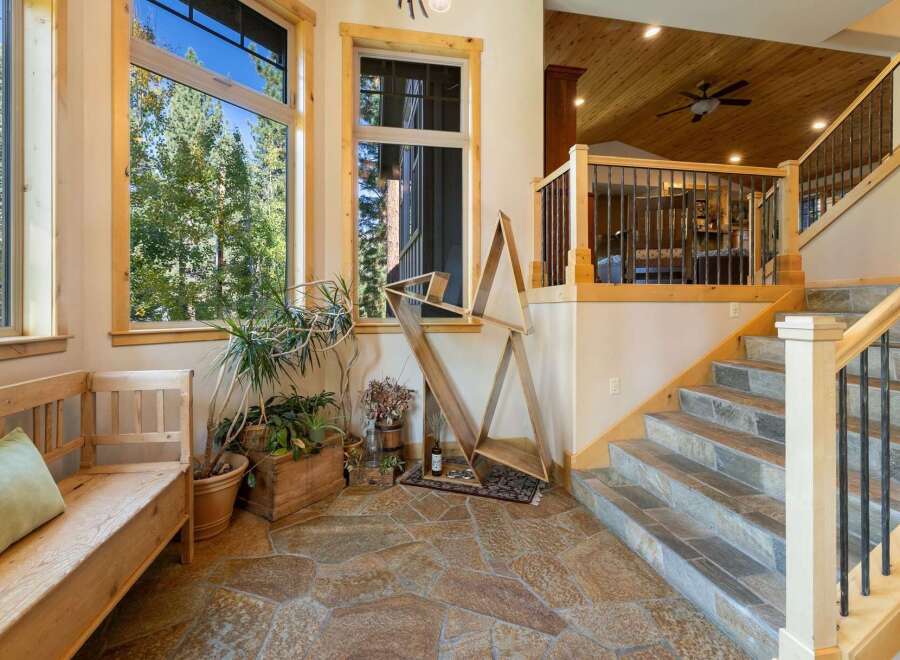Step into this inviting entryway featuring a rustic wooden bench and lush greenery, perfect for welcoming guests.