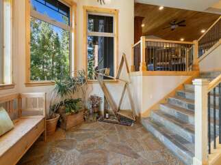 Step into this inviting entryway featuring a rustic wooden bench and lush greenery, perfect for welcoming guests.