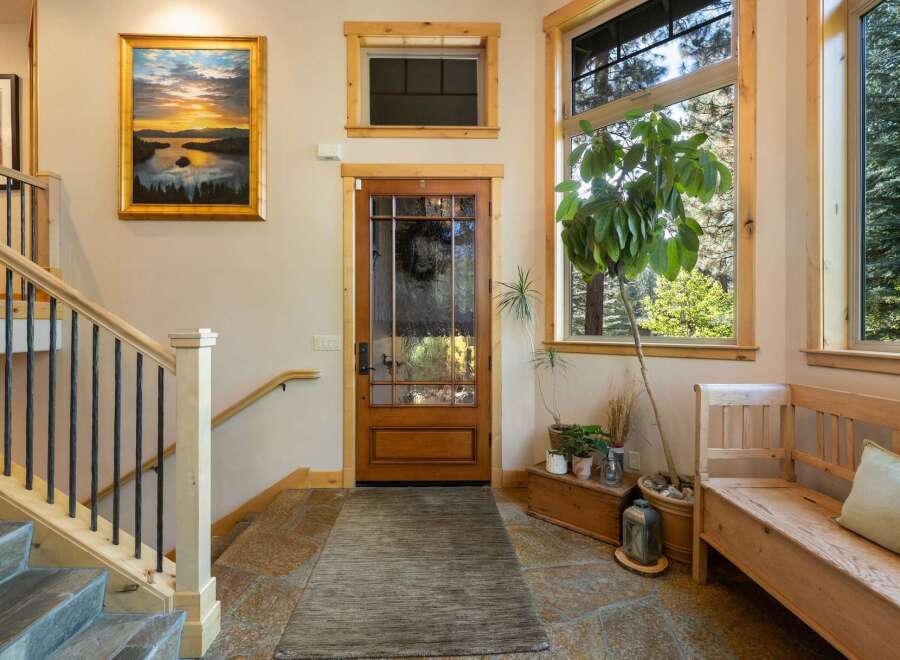 Step into a welcoming entryway featuring a beautiful landscape painting above a wooden staircase with wrought iron railings.
